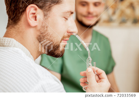 Man receives nasal inhalation. 72033569