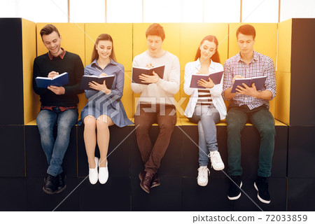 Young people sit and write something in notebook. 72033859