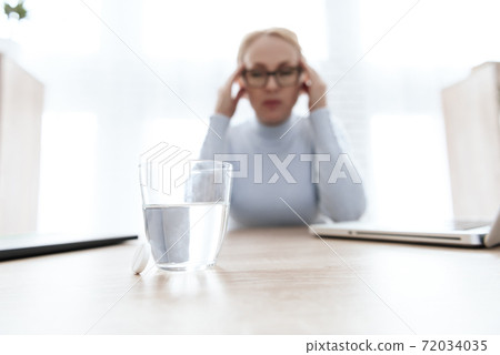 A glass of water stands on a table for sick girl. 72034035