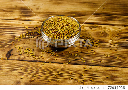 Fenugreek seeds in glass bowl on wooden table 72034038