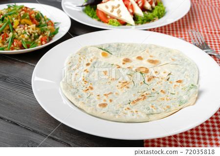 Homemade flatbread yantyk stuffed with cheese and greens Homemade flatbread yantyk stuffed with cheese and greens 72035818