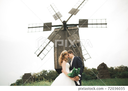 Stylish couple of happy newlyweds walking in the park on their wedding day with bouquet 72036035