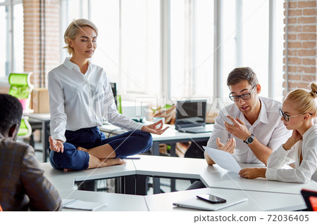 leader of company sits in yoga pose 72036405