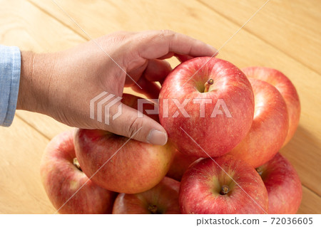 A man's hand reaching for an apple lined up with apples (November) A man's hand reaching for an apple lined up with apples (November) 72036605