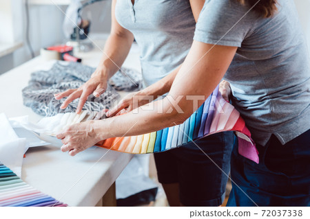 Hands on fabric pattern palette on studio table Hands on fabric pattern palette on studio table 72037338