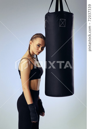 athletic woman in black boxing bandages leaning on punching bag athletic woman in black boxing bandages leaning on punching bag 72037339