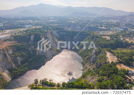 Aerial view of Grand Canyon Chonburi. Trucks dig coal mining or ore with black grunge ground in quarry with mountain hills. Nature landscape background in factory industry. Environment resources. 72037475