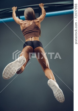 woman pumping up muscles pull-ups exercises in gym woman pumping up muscles pull-ups exercises in gym 72037998