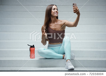Fitness woman with cell phone at workout in the gym Fitness woman with cell phone at workout in the gym 72038004