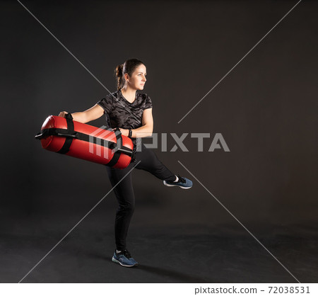 Fitness woman with Aqua Bag, sideways leg, moves. Engaged in sports on a black background Happy with beautiful eyes 72038531