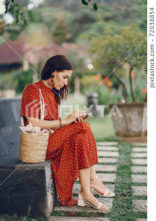 Girl in a red dress sitting and use the phone 72038854