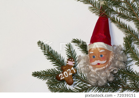 Christmas or winter composition. Santa's head with a red hat, white background, gingerbread with a face mask and 2021 with spruce branch decoration. Christmas background, Christmas, winter, new year Christmas or winter composition. Santa's head with a red hat, white background, gingerbread with a face mask and 2021 with spruce branch decoration. Christmas background, Christmas, winter, new year 72039151