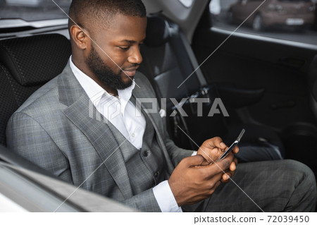 Closeup of african american entrepreneur using mobile phone in car 72039450