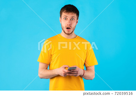 Surprised man using mobile phone at studio 72039516