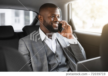 Happy black businessman talking on mobile phone in car Happy black businessman talking on mobile phone in car 72039719