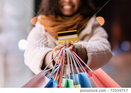 Unrecognizable black woman showing credit card and shopping bags Unrecognizable black woman showing credit card and shopping bags 72039757