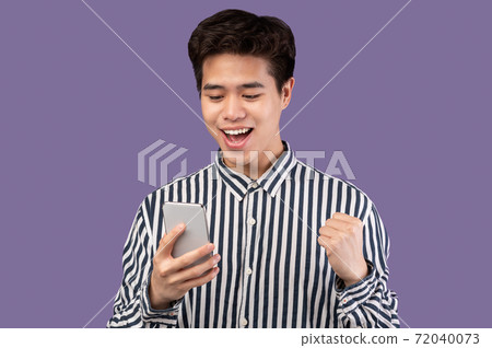 Excited asian man using mobile phone, celebrating online win 72040073