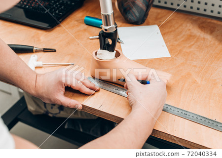 prosthetics technician checking prosthesis molds in a workshop 72040334