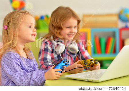 Two pretty little girls lying playing video game 72040424