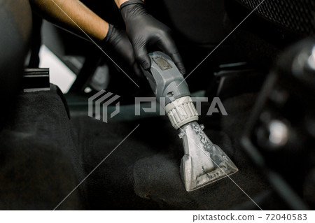 Cropped close up shot of hands of African male worker at auto service station, using vacuum cleaner in car, remowing the dust and sand. Vacuum cleaning inside the car Cropped close up shot of hands of African male worker at auto service station, using vacuum cleaner in car, remowing the dust and sand. Vacuum cleaning inside the car 72040583