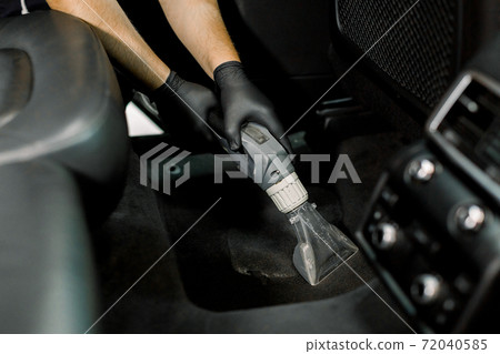 Details of car vacuum cleaning. Professional male worker using wet vacuum cleaner for dirty car interior. Auto car service worker using vacuum cleaner to wash car floor with foam Details of car vacuum cleaning. Professional male worker using wet vacuum cleaner for dirty car interior. Auto car service worker using vacuum cleaner to wash car floor with foam 72040585