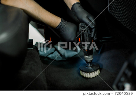 Close up cropped image of male hands in protective gloves, cleaning car interior and floor by chemical foam and scrubbing machine, electric brush. Car detailing and wash concept Close up cropped image of male hands in protective gloves, cleaning car interior and floor by chemical foam and scrubbing machine, electric brush. Car detailing and wash concept 72040589