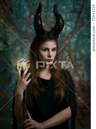 Maleficent demonic. young pretty dressed as a fairy with horns and magic ball 72041220