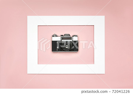 Flat lay old analog camera in the paper frame on pink background Flat lay old analog camera in the paper frame on pink background 72041226