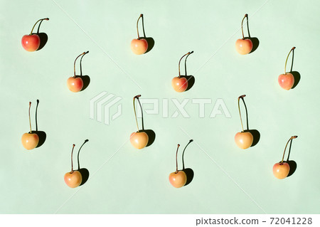 Yellow and pink cherries pattern on green background flat lay Yellow and pink cherries pattern on green background flat lay 72041228