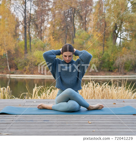 Young pretty woman doing yoga poses in the park autumn 72041229