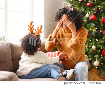 Ethnic son giving Christmas gift to mother. Ethnic son giving Christmas gift to mother. 72041660