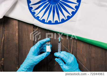 Hands of doctor wearing gloves holding coronavirus vial vaccine 72044961