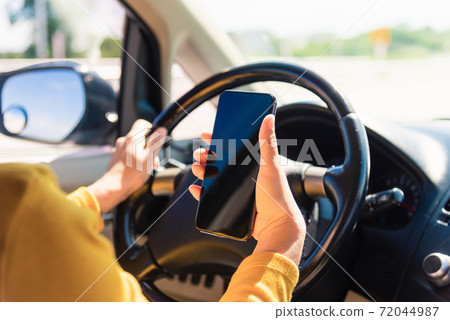 woman inside a car and using a hand holding mobile smartphone woman inside a car and using a hand holding mobile smartphone 72044987