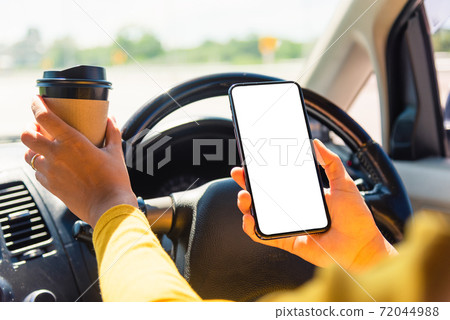 woman drinking hot coffee takeaway cup inside a car and using smartphone woman drinking hot coffee takeaway cup inside a car and using smartphone 72044988