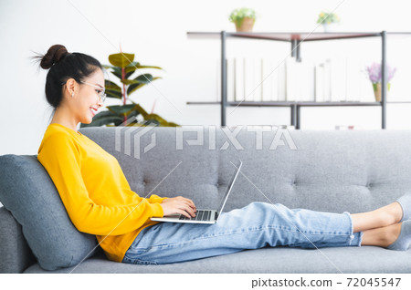Beautiful young asian woman using computer laptop working on sofa in living room Beautiful young asian woman using computer laptop working on sofa in living room 72045547