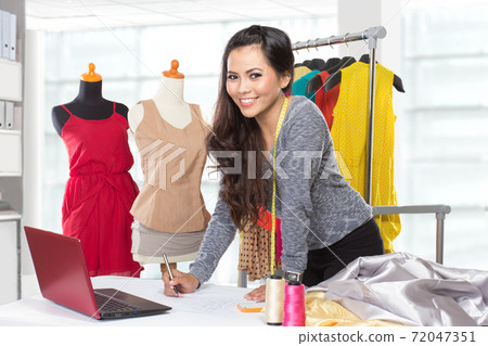 Young asian designer woman using a laptop and smiling,clothes ha Young asian designer woman using a laptop and smiling,clothes ha 72047351