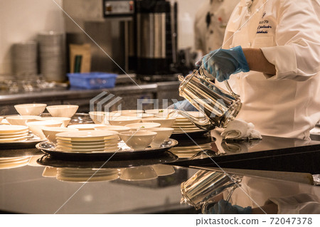 Image of a person working in the kitchen wearing gloves and a mask Image of a person working in the kitchen wearing gloves and a mask 72047378