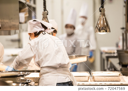 在廚房裡戴著手套和口罩工作的人的形象 72047569