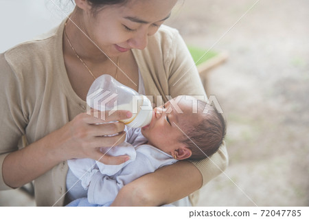 cute newborn baby being fed by her mother using bottle 72047785