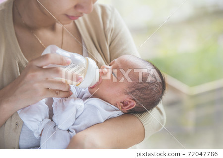 cute newborn baby being fed by her mother using bottle 72047786