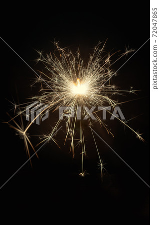 Glittering burning sparkler on black Glittering burning sparkler on black 72047865