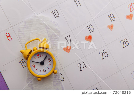 Calendar, menstrual pads and yellow alarm clock close-up 72048216