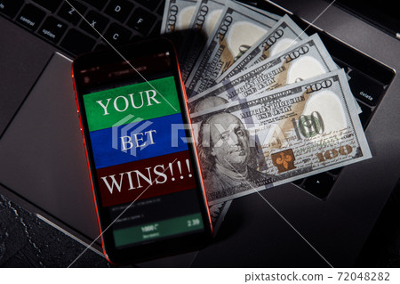 Smartphone with gambling mobile application and money banknotes on a keyboard. Sport and betting concept 72048282