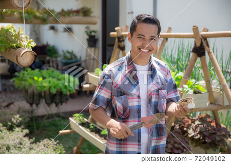 man with small plant in his farm man with small plant in his farm 72049102