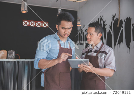 coffee shop owner discussing with his employee using tablet coffee shop owner discussing with his employee using tablet 72049151