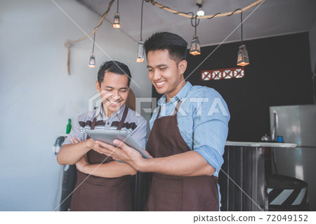 coffee shop owner discussing with his employee using tablet coffee shop owner discussing with his employee using tablet 72049152