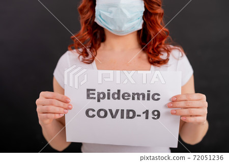 A faceless redhead woman in a medical mask holds an announcement about the epidemic of coronavirus. Quarantine. Pandemic covid-19. A faceless redhead woman in a medical mask holds an announcement about the epidemic of coronavirus. Quarantine. Pandemic covid-19. 72051236