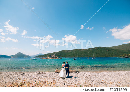 bride and groom are hugging on the beach of the Mamula island against the backdrop of the ancient fortress bride and groom are hugging on the beach of the Mamula island against the backdrop of the ancient fortress 72051299