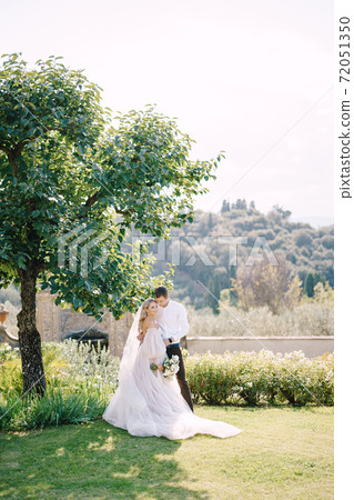 Wedding in Florence, Italy, in an old villa-winery. Bride and groom in the shade of a tree. Wedding couple walks in the garden. Wedding in Florence, Italy, in an old villa-winery. Bride and groom in the shade of a tree. Wedding couple walks in the garden. 72051350