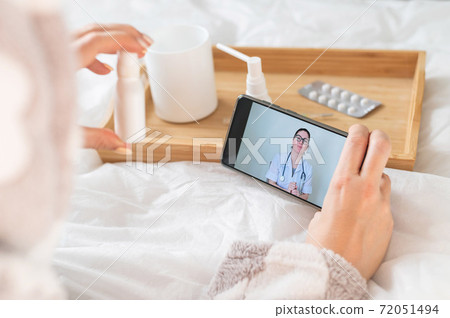The doctor gives an online consultation to the patient. The woman in quarantine communicates with the attending physician The doctor gives an online consultation to the patient. The woman in quarantine communicates with the attending physician 72051494